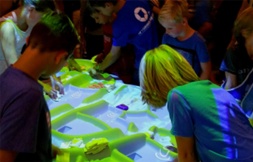 Kinderen buigen zich over een groen verlichte speeltafel