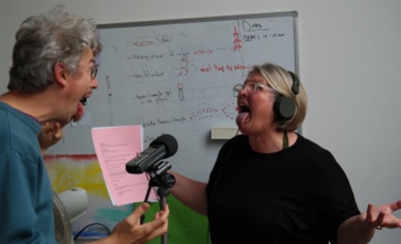 Twee mensen zingen en lachen voor een microfoon