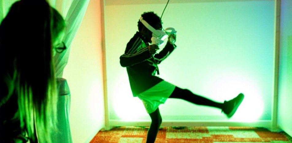 Iemand met een VR-bril maakt een trap in een groen verlichte ruimte op Cinekid