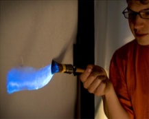 Een jongen schijnt met een zaklamp blauw licht op de muur