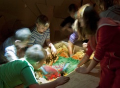Kinderen spelen met hun handen in een verlichte zandbak